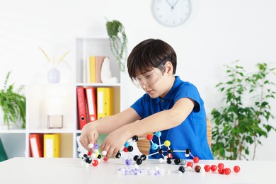 Photo of Boy making DNA structure model at desk indoors