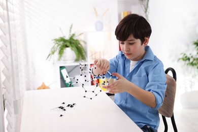 Photo of Boy making DNA structure model at desk indoors. Space for text