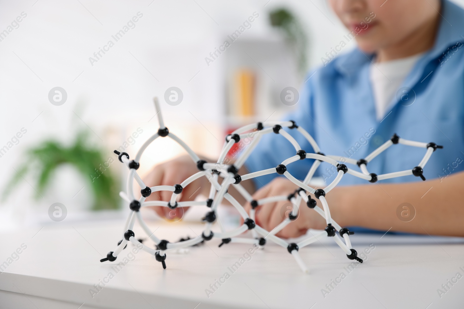 Photo of Boy making DNA structure model at desk indoors, closeup. Space for text