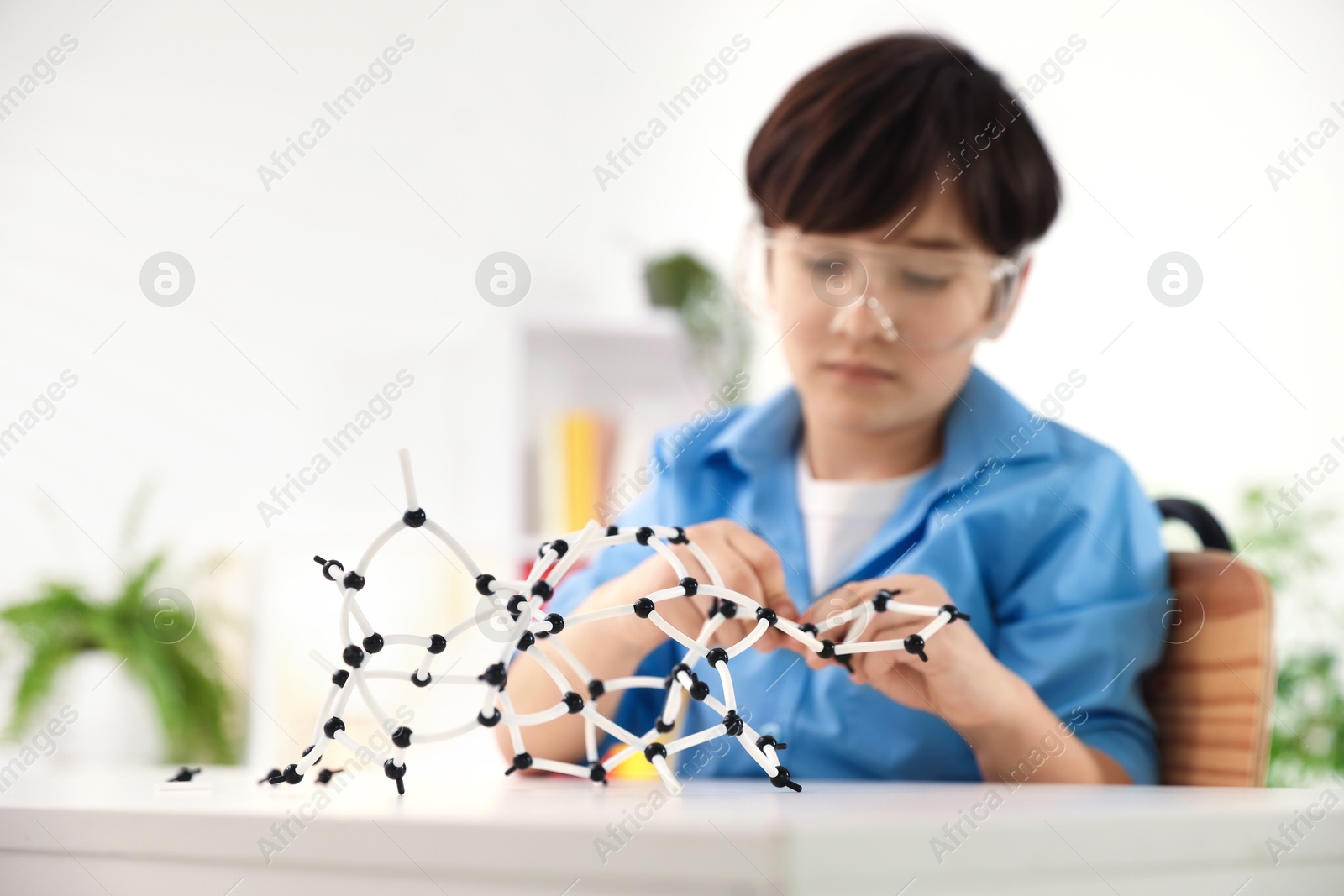 Photo of Boy making DNA structure model at desk indoors, selective focus