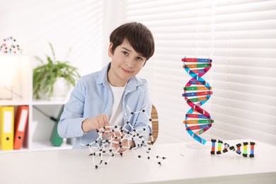 Photo of Boy making DNA structure model at desk indoors