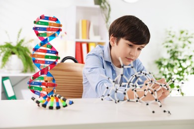 Photo of Boy making DNA structure model at desk indoors