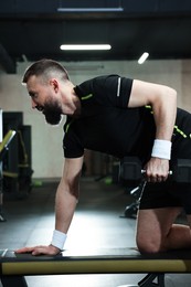 Photo of Athletic man training with dumbbell in gym