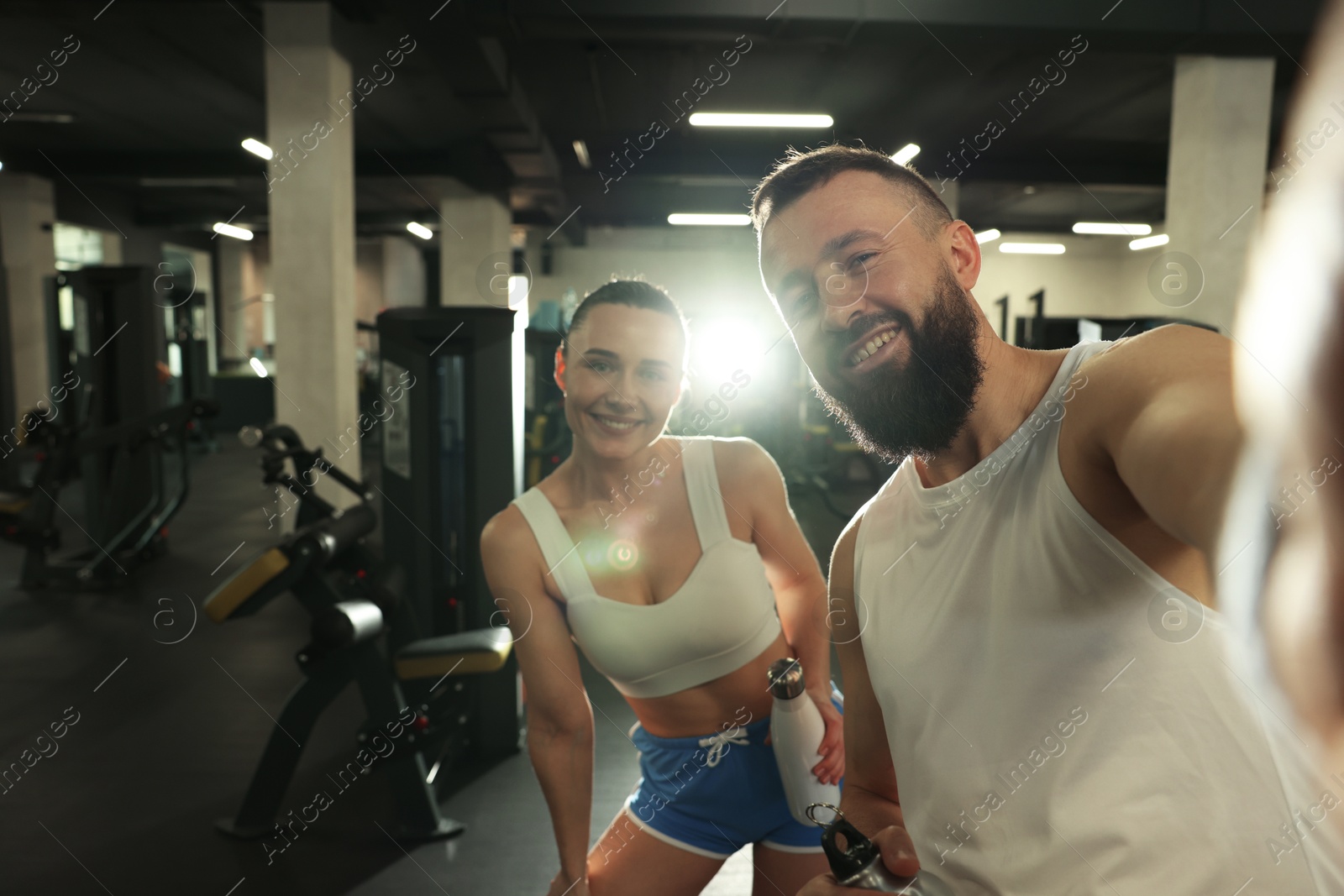 Photo of Couple with water bottles taking selfie after training in gym