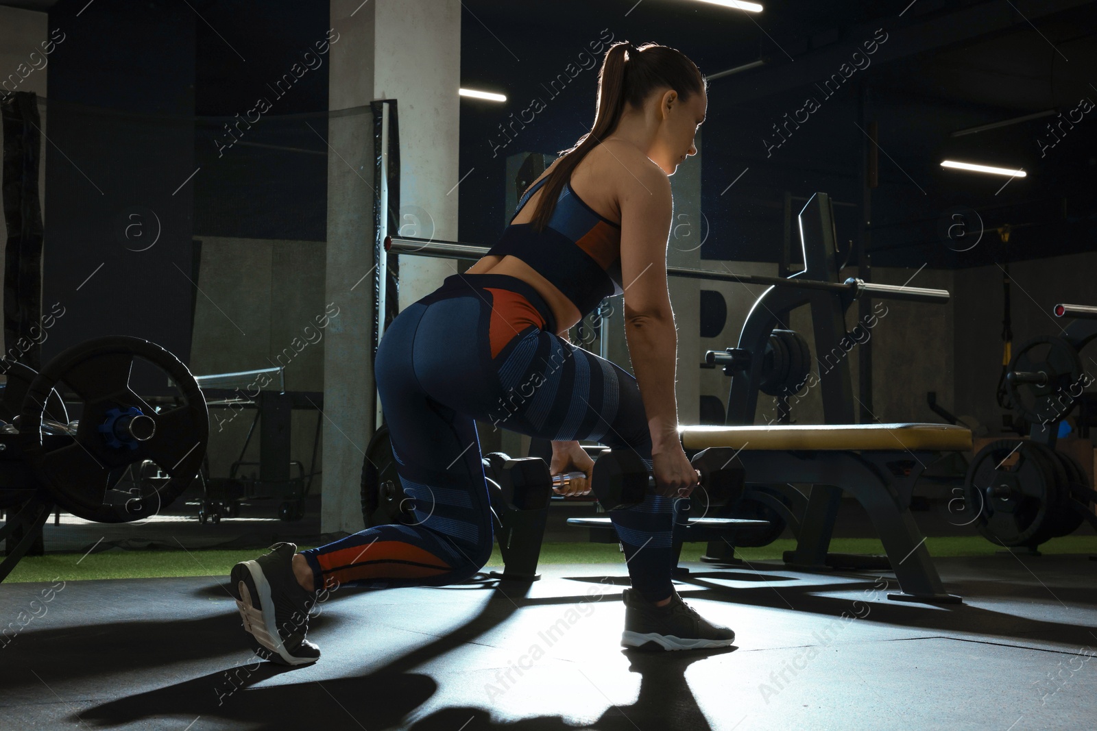 Photo of Athletic woman training with dumbbells in gym