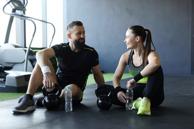 Photo of Couple with water bottles and kettlebells in gym