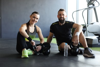 Photo of Couple with water bottles and kettlebells in gym