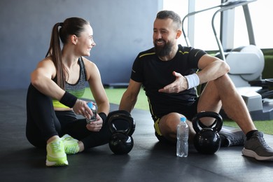 Photo of Couple with water bottles and kettlebells in gym