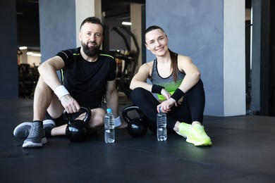 Photo of Couple with water bottles and kettlebells in gym