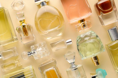 Photo of Bottles of various perfumes on beige background, flat lay