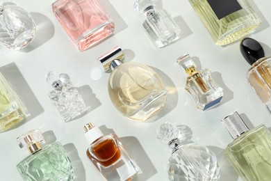 Photo of Bottles of various perfumes on light background, flat lay