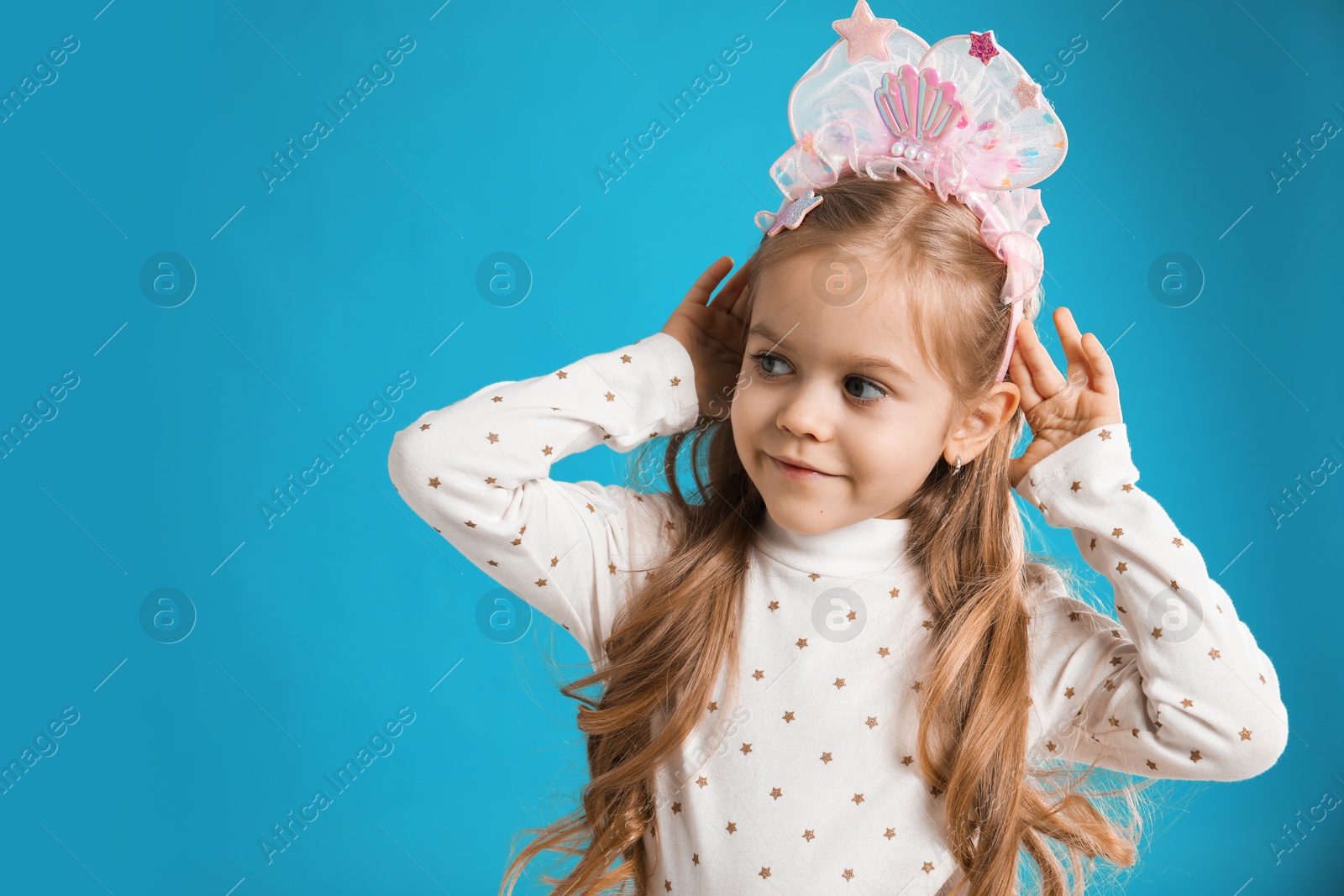 Photo of Cute little girl with beautiful headband on blue background. Space for text