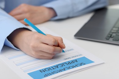 Photo of Student filling scholarship application form at white table, closeup