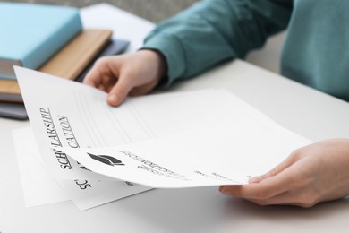 Photo of Student with scholarship application forms at white table, closeup