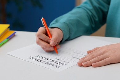 Photo of Student filling scholarship application form at white table, closeup