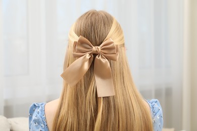 Photo of Woman with beautiful hair bow indoors, back view