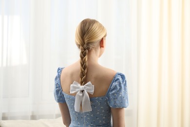 Photo of Woman with beautiful hair bow indoors, back view