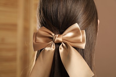 Photo of Woman with beautiful hair bow on blurred background, back view