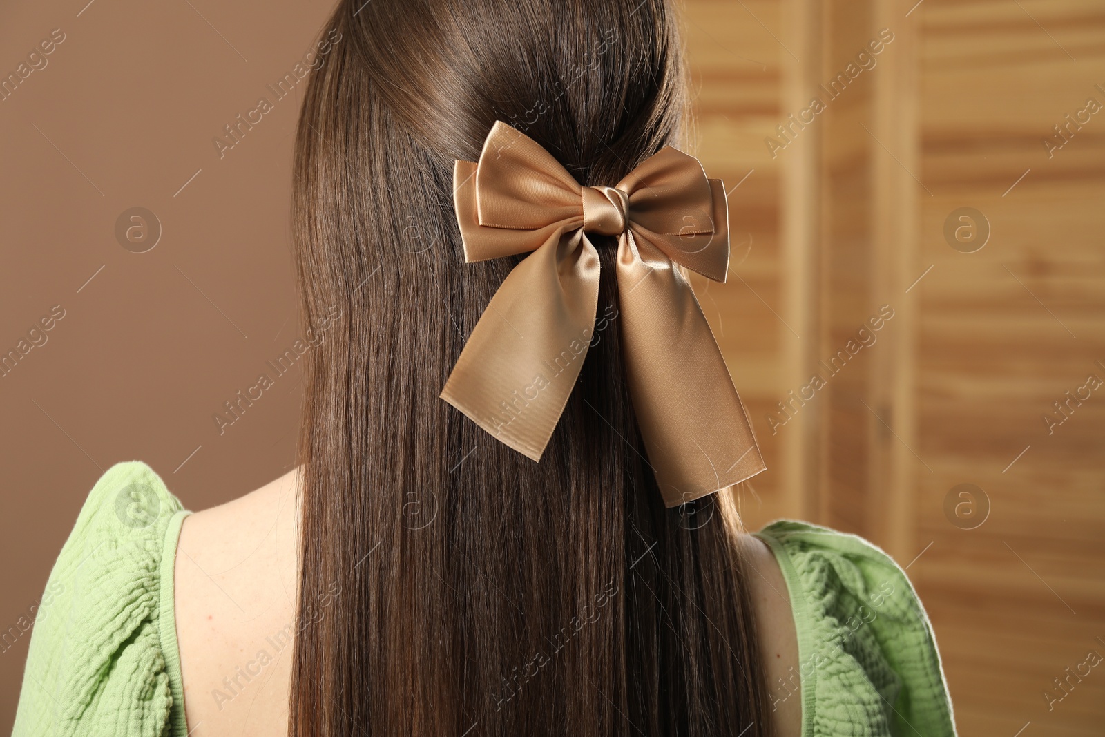 Photo of Woman with beautiful hair bow on blurred background, back view