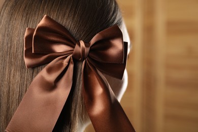 Photo of Woman with beautiful hair bow on blurred background, closeup. Space for text