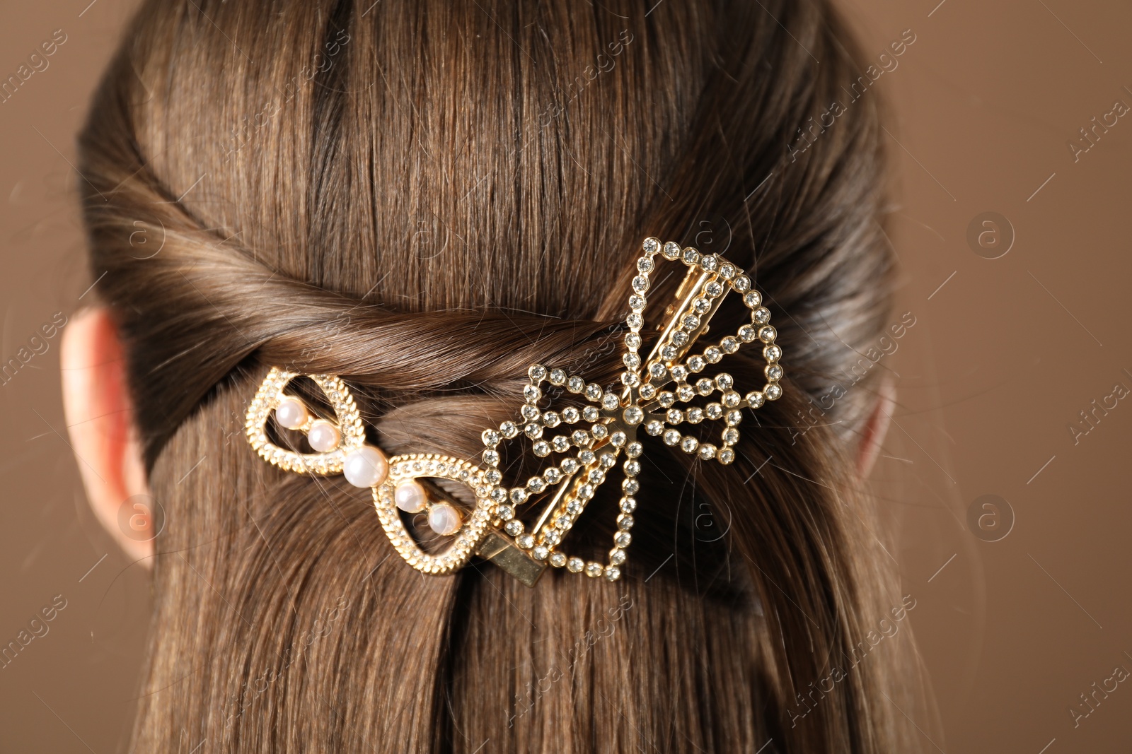 Photo of Woman with beautiful hair clips on brown background, closeup