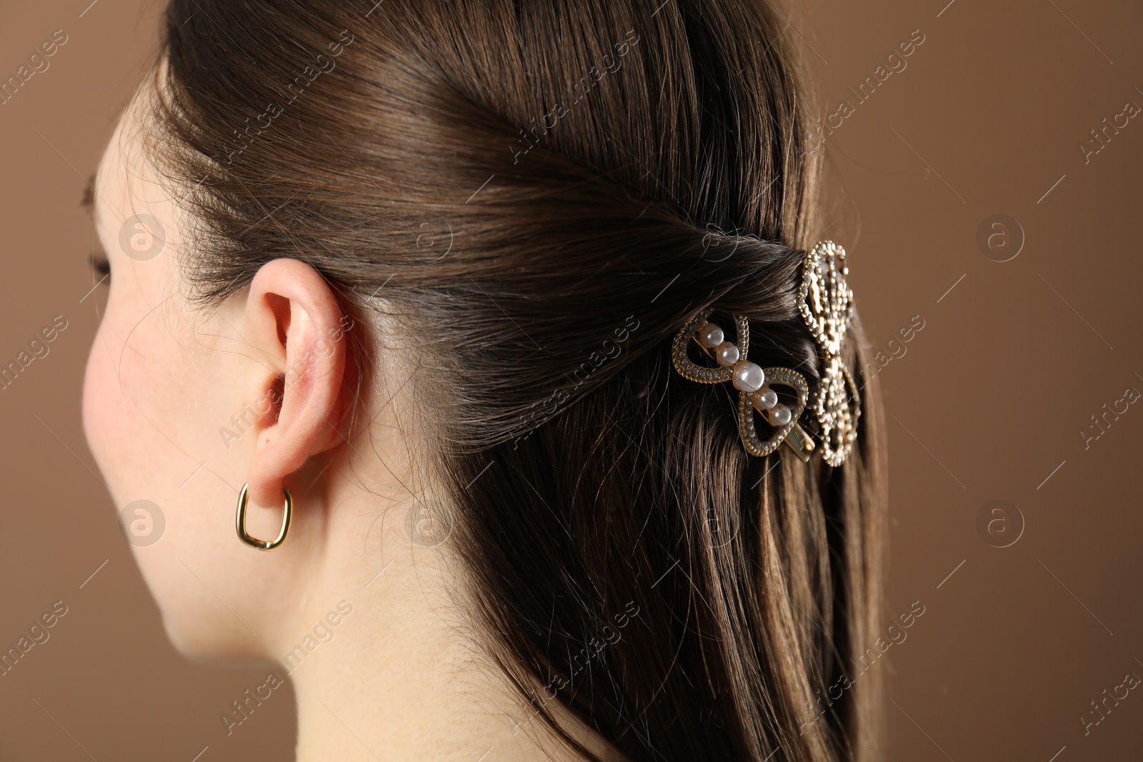 Photo of Woman with beautiful hair clips on brown background, closeup