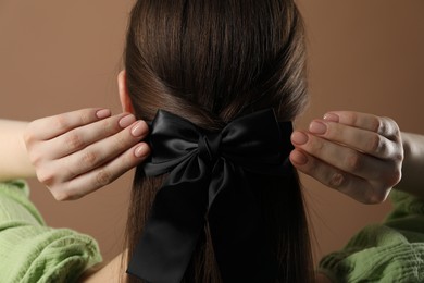 Photo of Woman with beautiful hair bow on brown background, back view