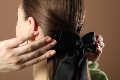 Photo of Woman with beautiful hair bow on brown background, closeup