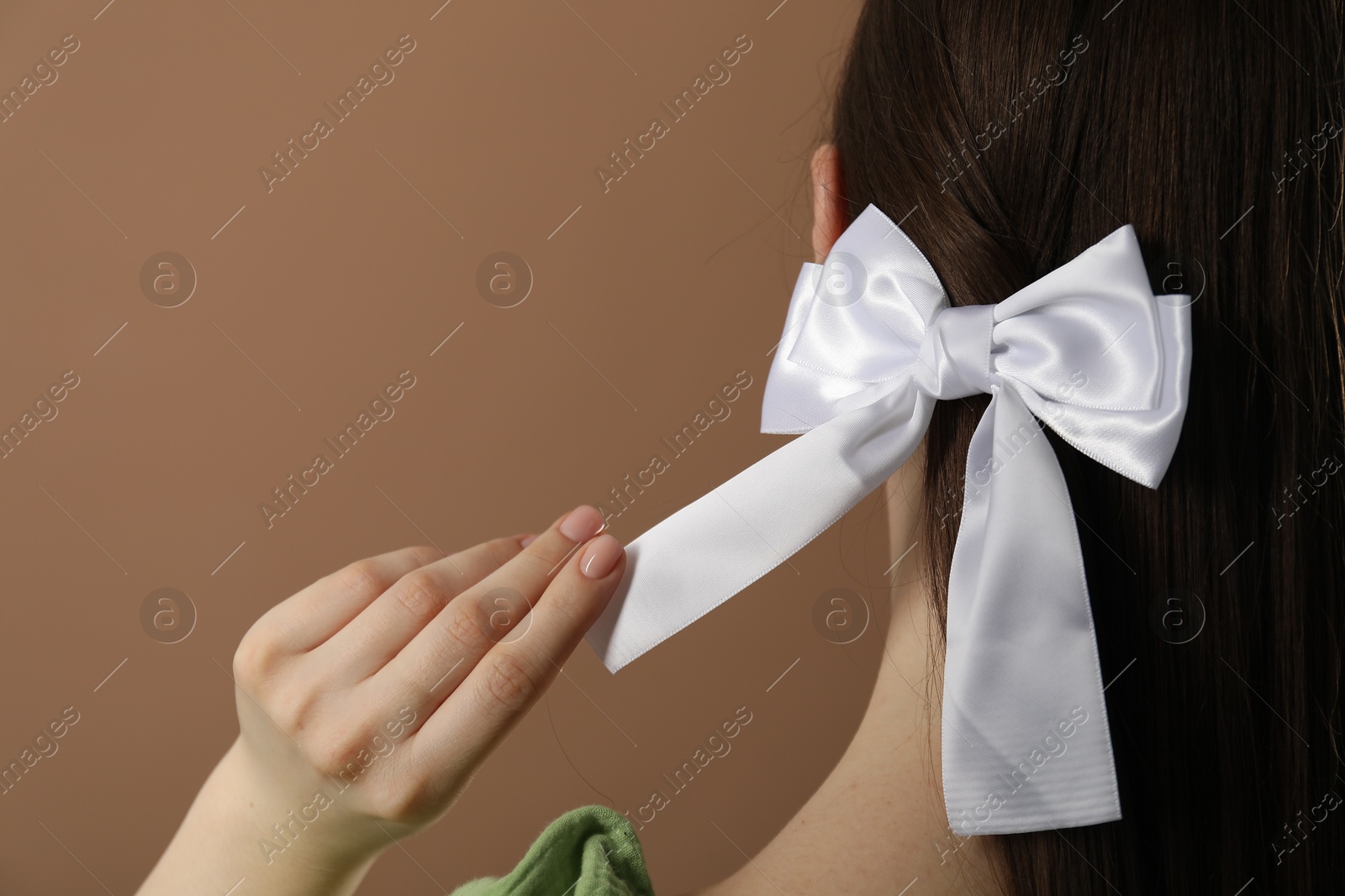 Photo of Woman with beautiful hair bow on brown background, closeup