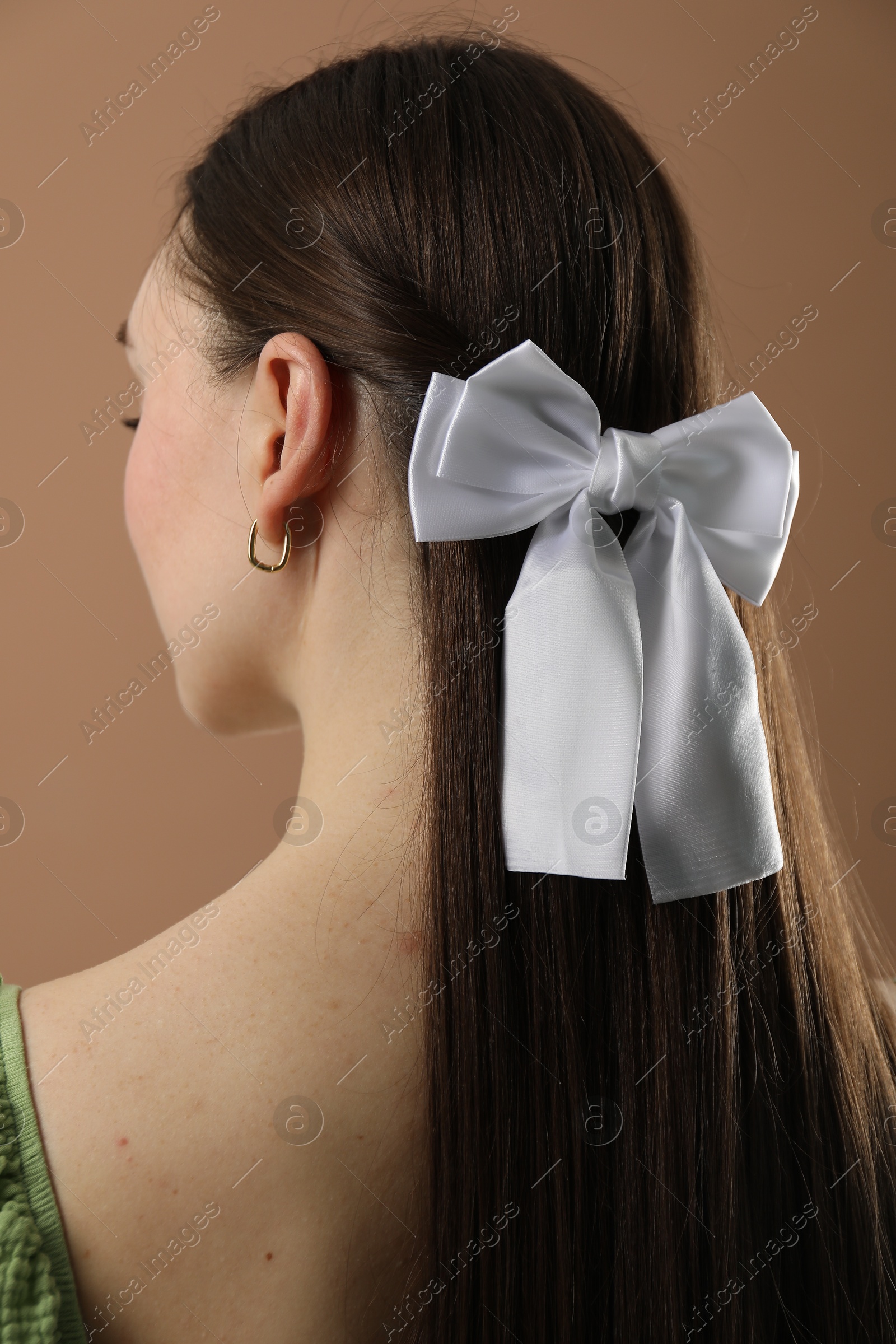 Photo of Woman with beautiful hair bow on brown background