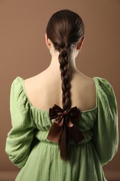 Photo of Woman with beautiful hair bow on brown background, back view