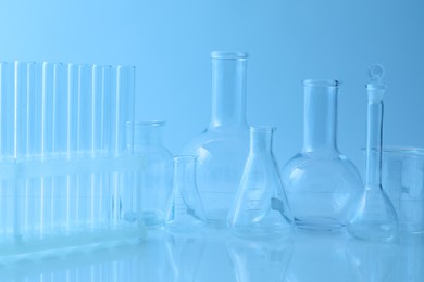 Photo of Different laboratory glassware on light blue background