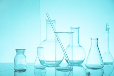 Photo of Laboratory glassware on mirror surface against light blue background