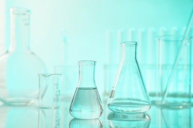 Photo of Laboratory glassware on mirror surface against turquoise background