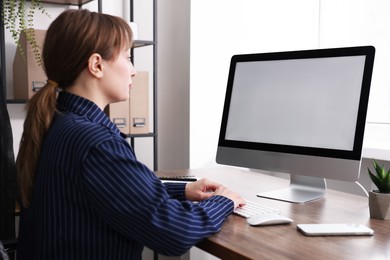 Photo of Woman working on computer at wooden desk in office. Mockup for design