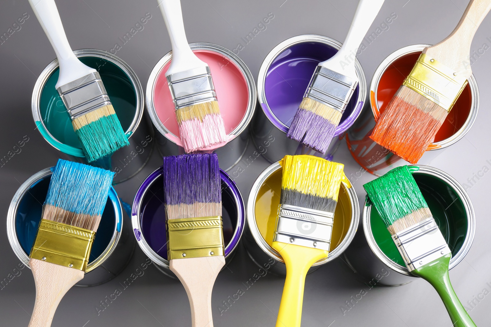 Photo of Cans of paint and brushes on grey background, flat lay