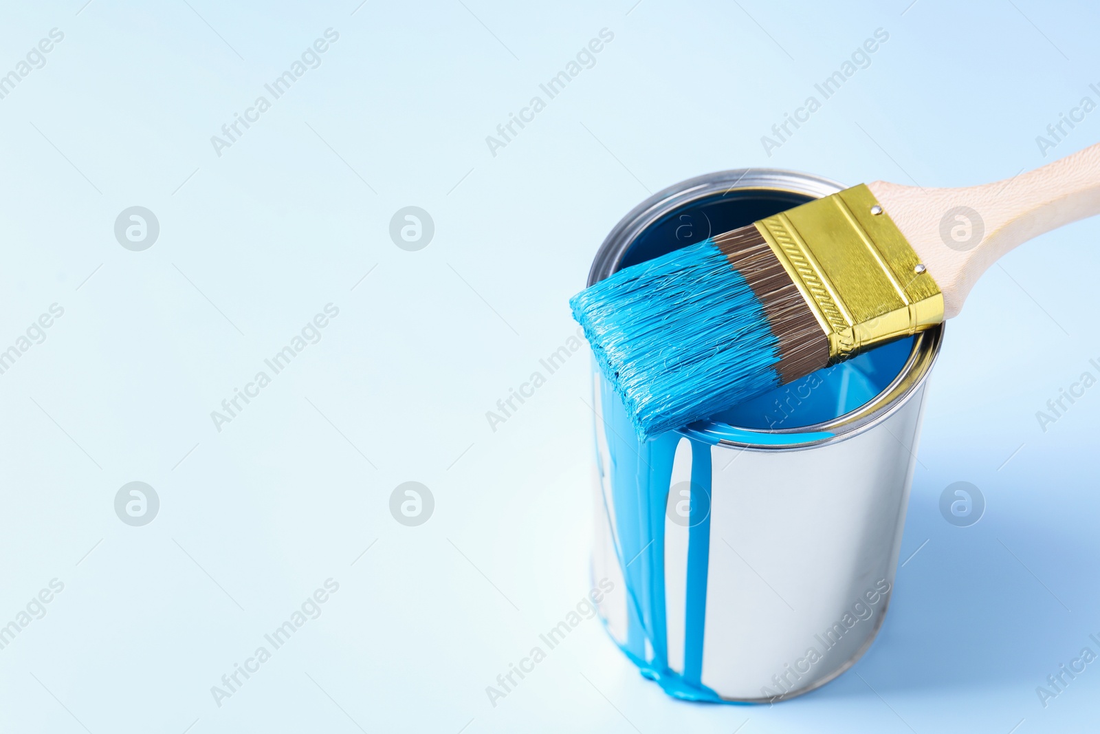 Photo of Can of blue paint and brush on light background. Space for text