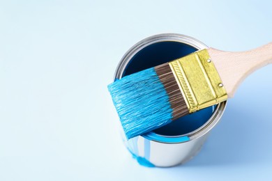 Photo of Can of blue paint and brush on light background, above view