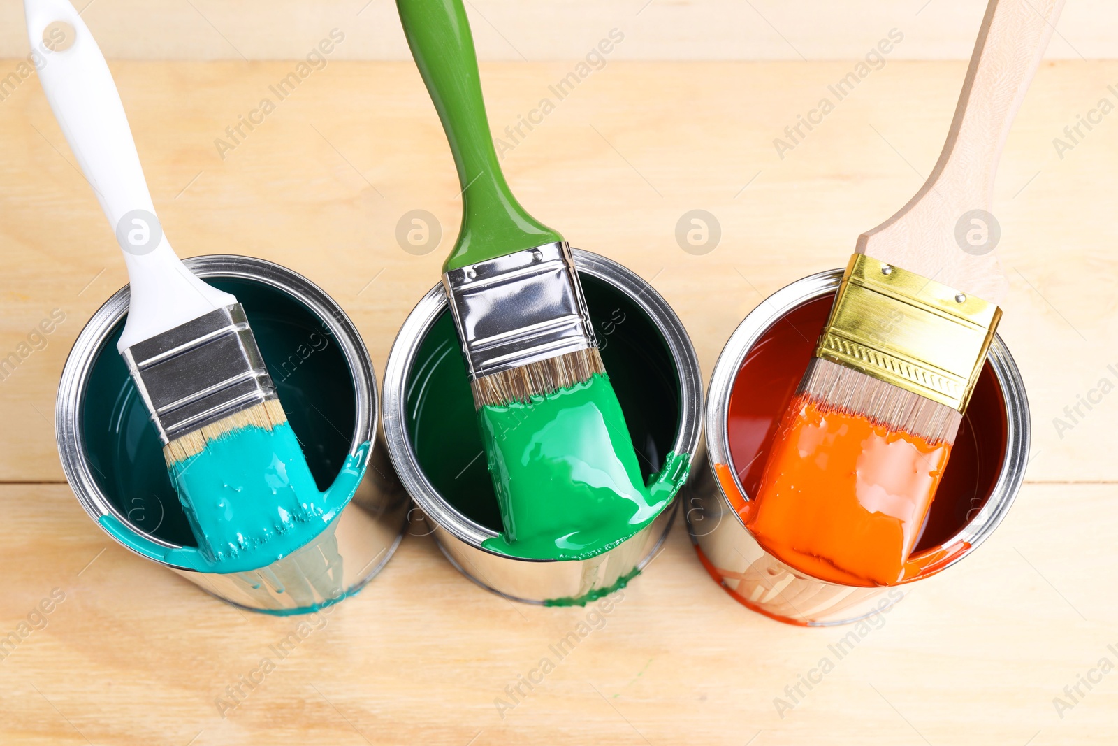 Photo of Cans of paint and brushes on wooden table, flat lay