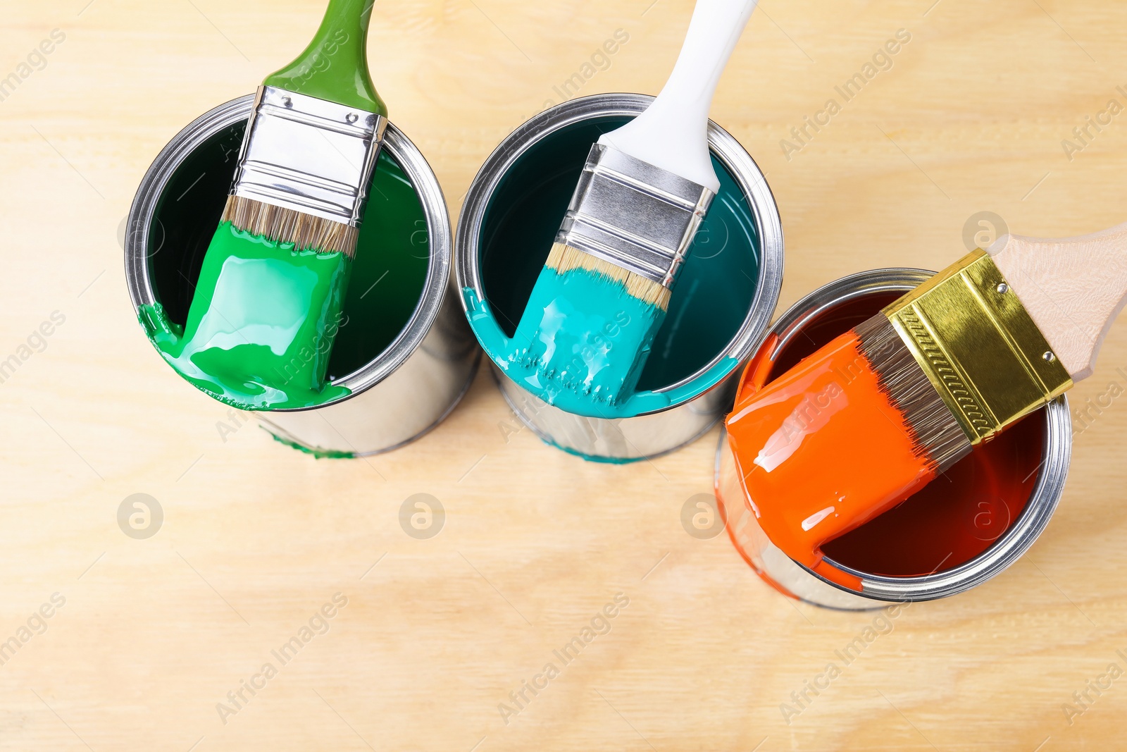 Photo of Cans of paint and brushes on wooden table, flat lay