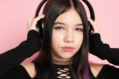 Photo of Teenage girl with headphones posing on pink background. Makeup and clothes in anime style