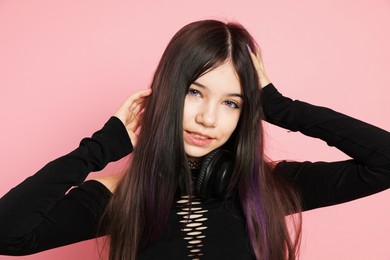 Photo of Teenage girl with headphones posing on pink background. Makeup and clothes in anime style