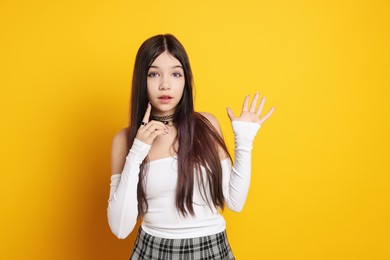 Photo of Teenage girl wearing stylish clothes and accessories on orange background. Makeup in anime style