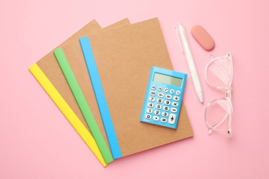 Photo of Copybooks, glasses and other different stationery on pink background, flat lay