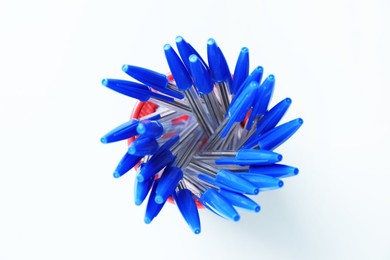 Photo of Many ballpoint pens in holder on light grey background, top view