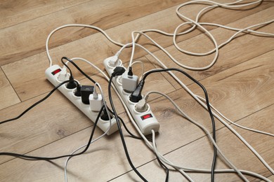 Photo of Extension power boards overloaded with plugs on wooden floor