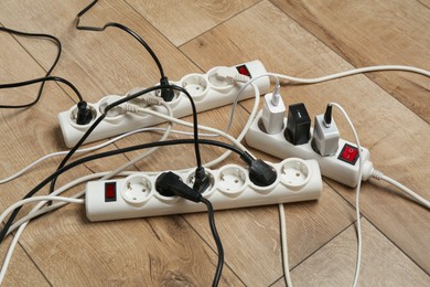 Photo of Extension power boards overloaded with plugs on wooden floor