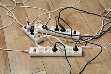 Photo of Extension power boards overloaded with plugs on wooden floor