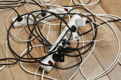 Photo of Extension power boards overloaded with plugs on wooden floor