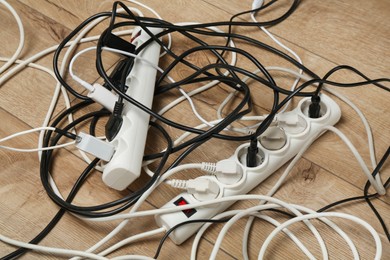 Photo of Extension power boards overloaded with plugs on wooden floor